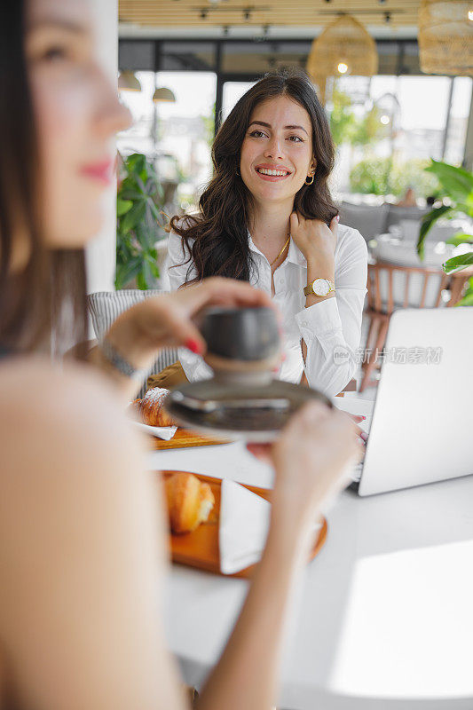 Beautiful businesswoman sitting in café with her colleague and exchanging ideas over coffee